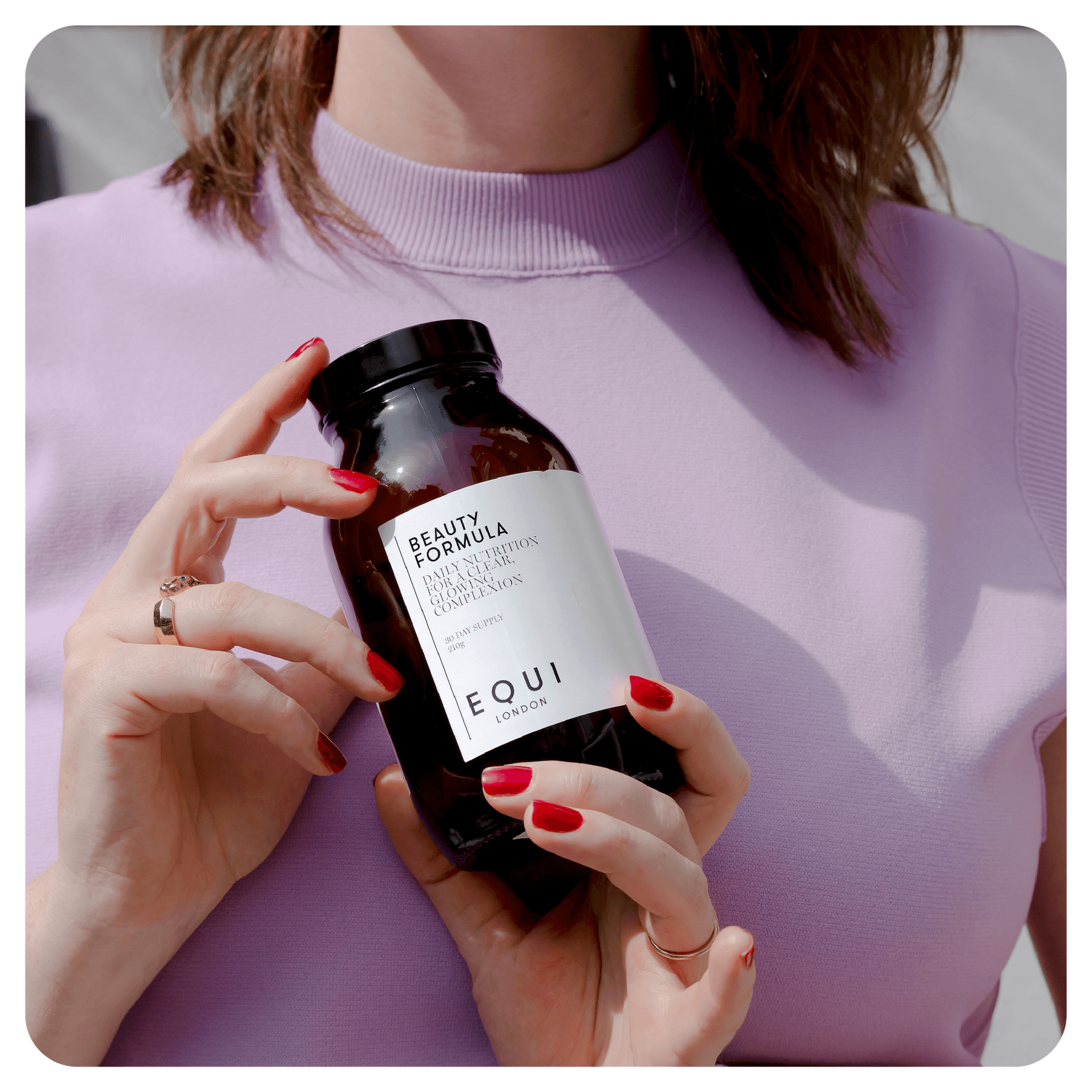 Women with a lilac top holding a jar of Beauty Formula