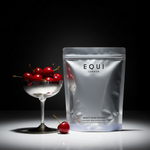 Spotlight on a pouch of Equi London Beauty Sleep Edition with a glass of cherries on a dark background