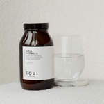 Jar of Well Formula by EQUI London next to a glass on a light background
